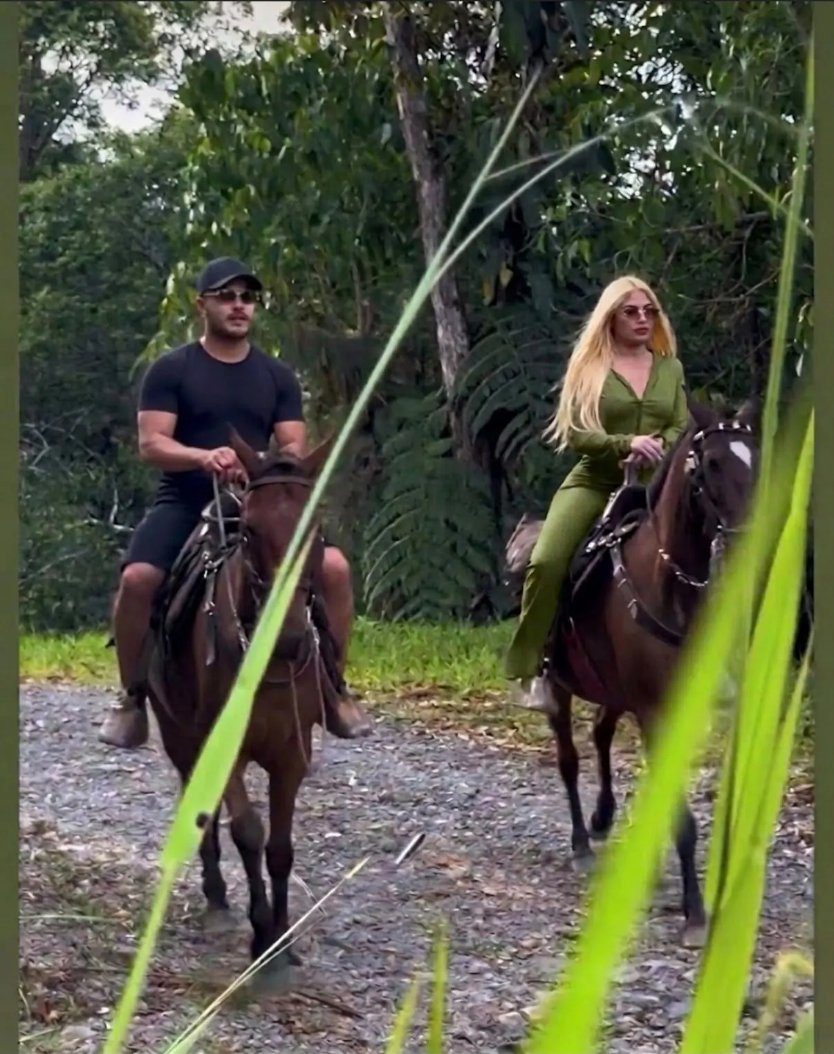 Pareja en cabalgata por un camino entre árboles